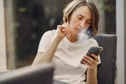 Personne qui vapote et regarde son téléphone