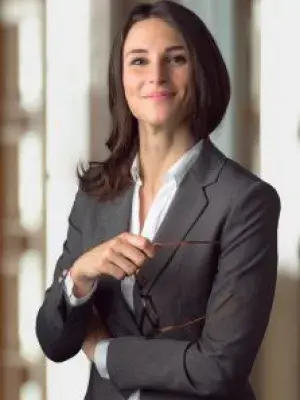 femme regarde la caméra de face et tient une paire de lunettes